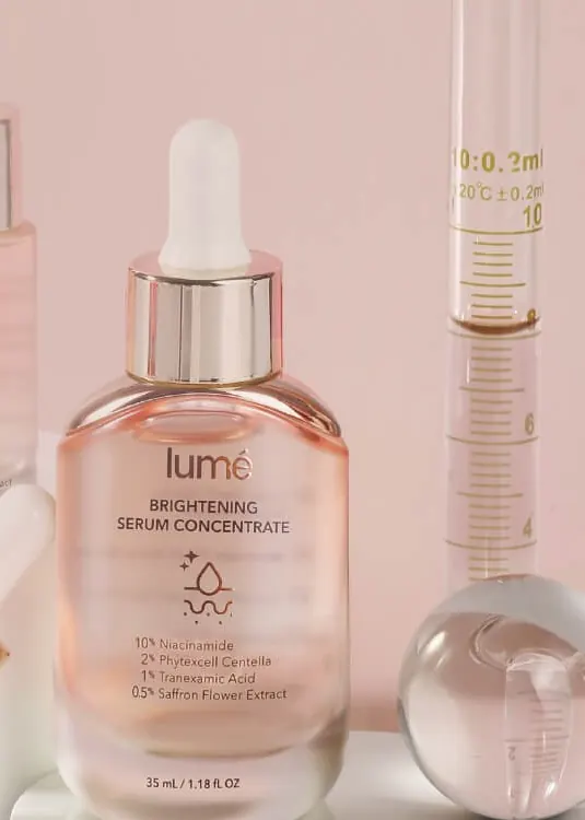 Botol Brightening Serum Concentrate 35 mL di atas alas putih, botol 10 mL dan gelas ukur