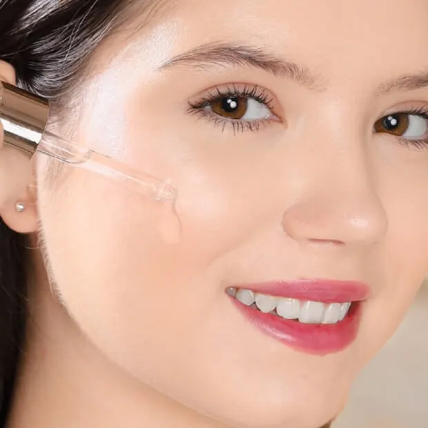 Model tersenyum meneteskan Brightening Serum Concentrate ke pipi dengan pipet