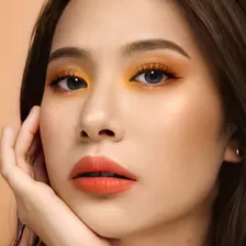 Model berambut panjang dengan eyeshadow kuning-oranye dan bibir oranye