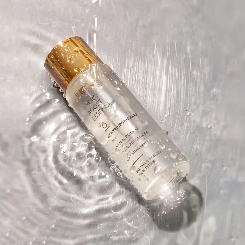Botol Lume Hydro Boost Essence penuh embun di atas air beriak