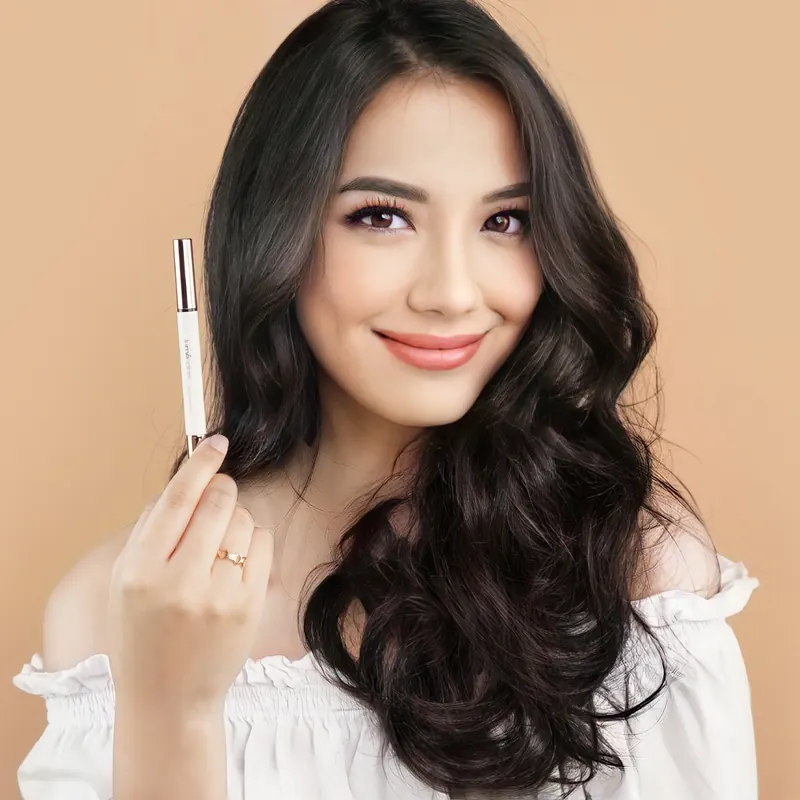 Model berambut ikal panjang tersenyum sambil memegang pensil Lumécolors Eyeconic Duo