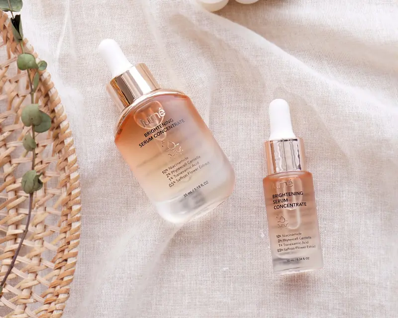 Dua botol pipet Lume Brightening Serum Concentrate di atas kain linen putih