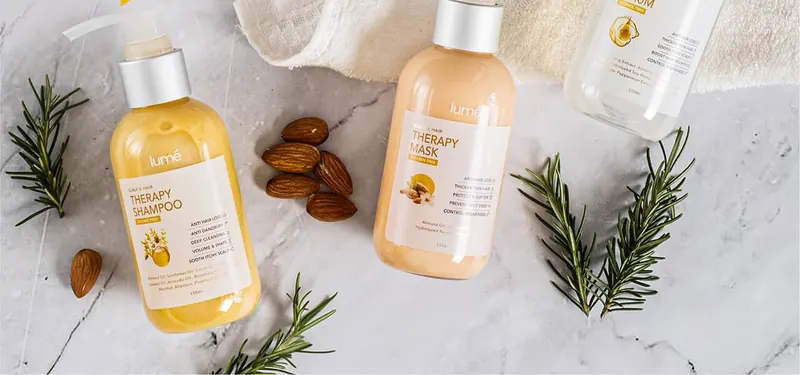 Therapy Shampoo, Therapy Mask dan Therapy Serum di atas marmer dengan kacang almond dan rosemary