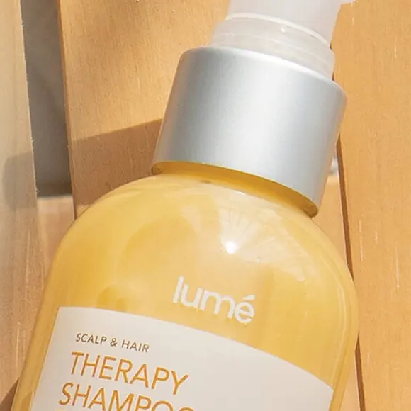 Botol Therapy Shampoo 150 mL di atas bilah kayu yang terkena sinar matahari
