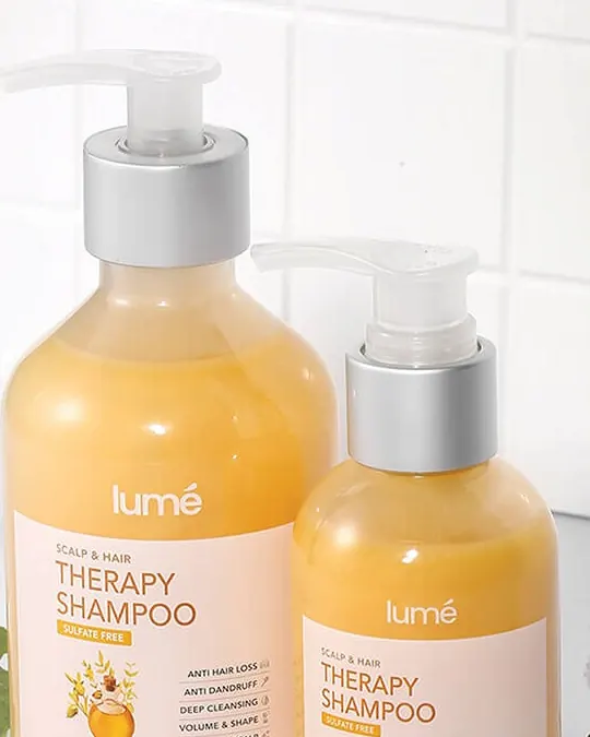 Therapy Shampoo ukuran 320 mL dan 150 mL di atas meja kamar mandi